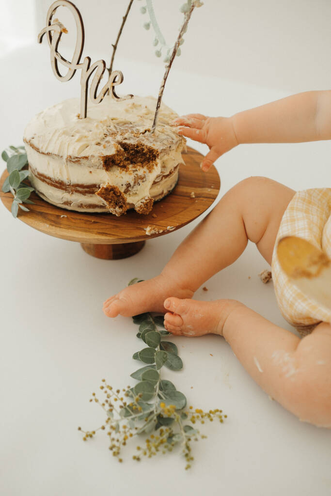 Cute chubby legs and hands smashing the cake for their first birthday